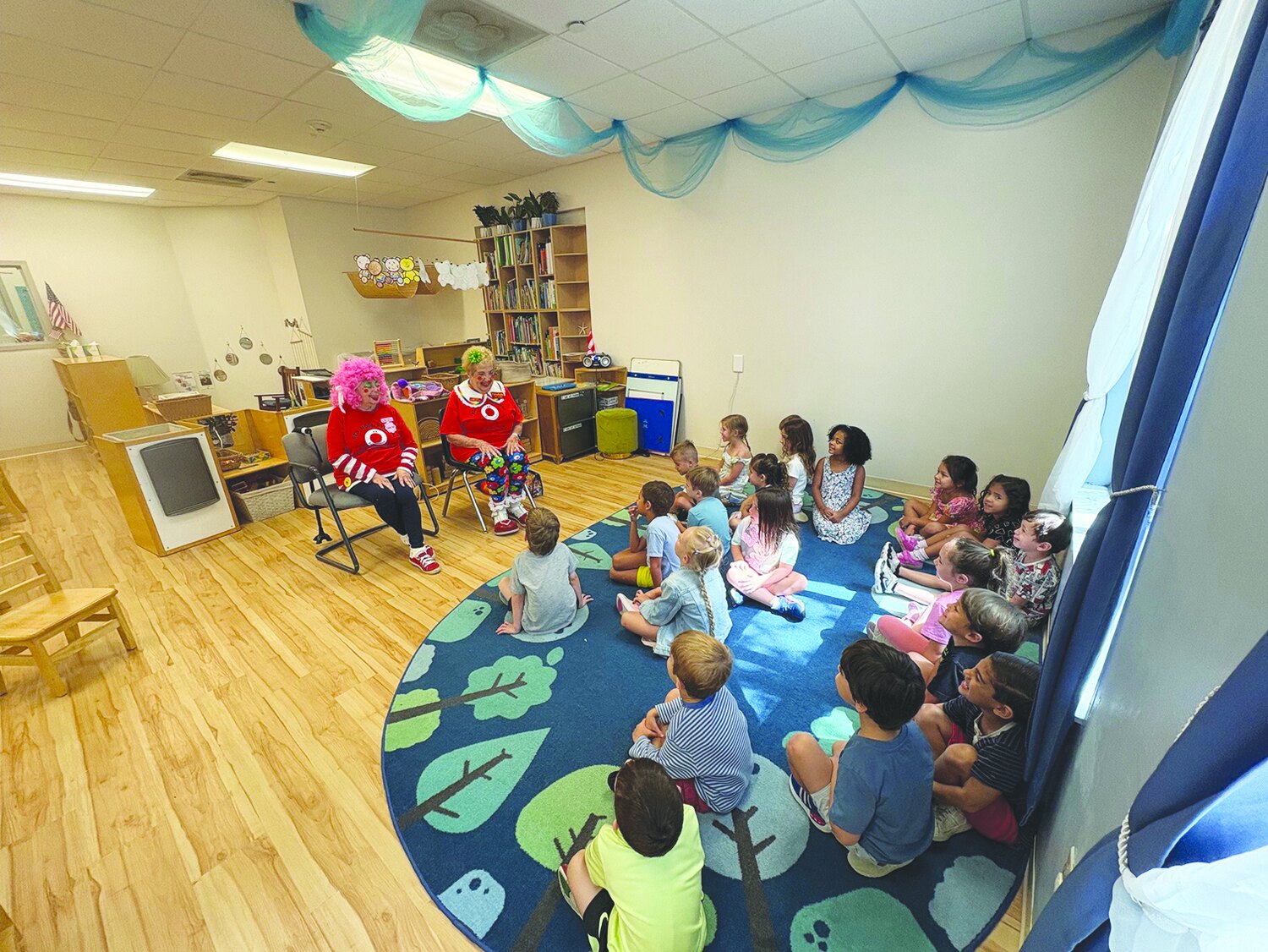 Two clowns performing for children seated on a story-time rug