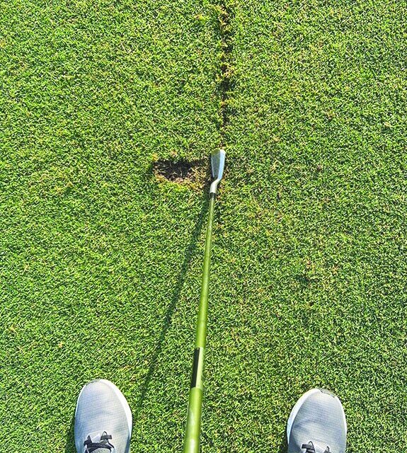 Golfer looking down at an iron behind a practice line drawn in the turf