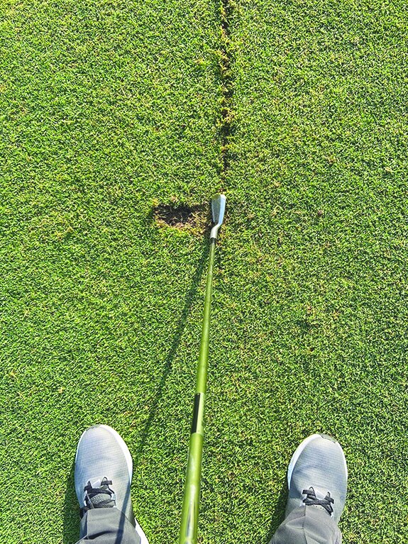 Golfer looking down at an iron behind a practice line drawn in the turf