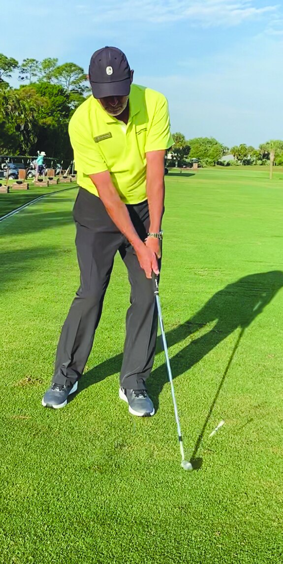 Golf instructor set up over a ball on the fairway demonstrating arc depth
