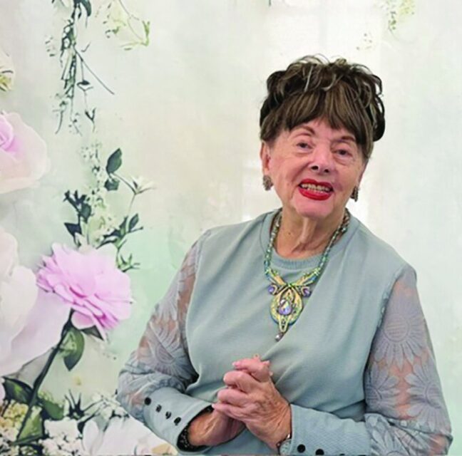 Author Judith Levy seated in front of a floral backdrop