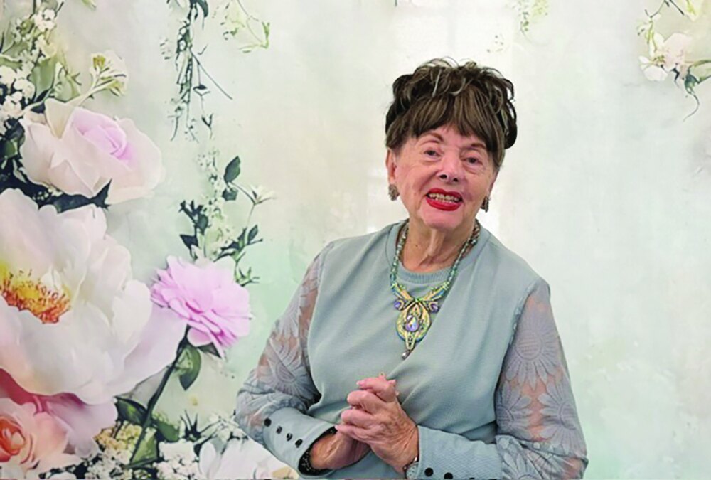 Author Judith Levy seated in front of a floral backdrop