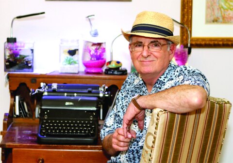 Columnist Bill Gralnick seated beside a vintage typewriter