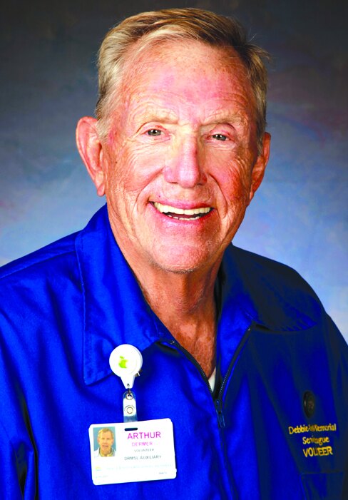 Arthur Dermer wearing a blue volunteer jacket and name badge
