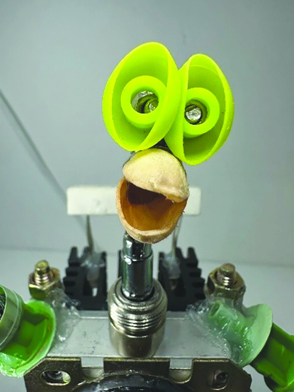 Found-object sculpture with bright green eyes by Oliver Sarkis
