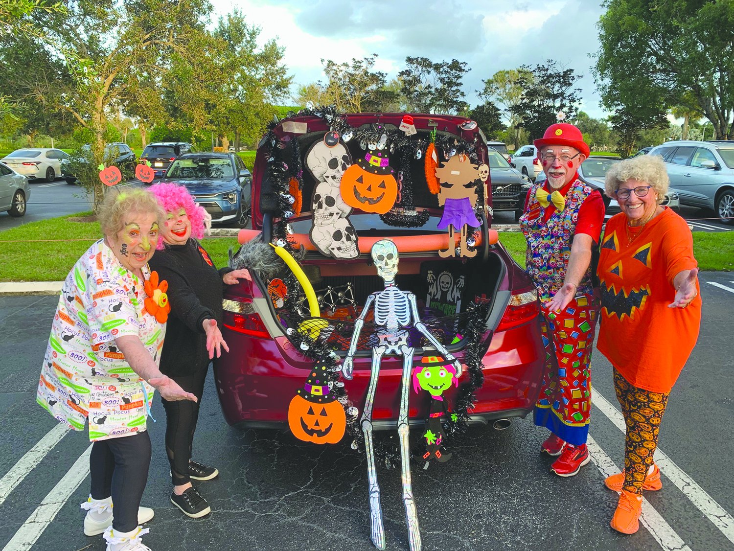 Clowns beside a Halloween-decorated car trunk at a Trunk or Treat event